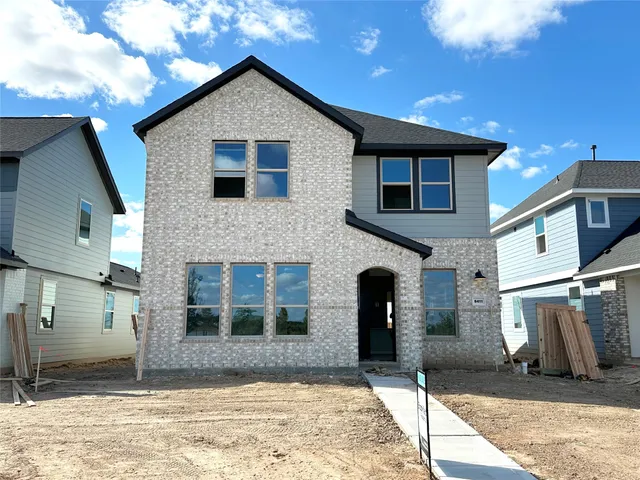 a view of a brick house with many windows and a yard