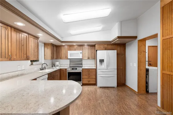 a large white kitchen with a refrigerator a stove top oven a sink and dishwasher