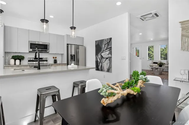 a kitchen with stainless steel appliances granite countertop a sink a stove a dining table and chairs