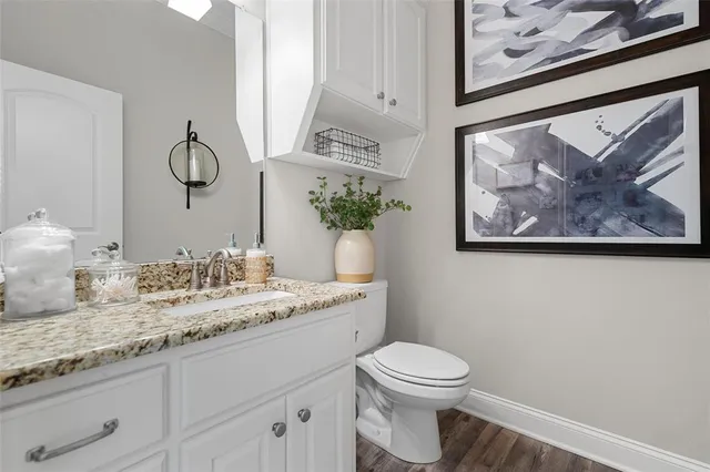 a bathroom with a granite countertop toilet a sink and mirror