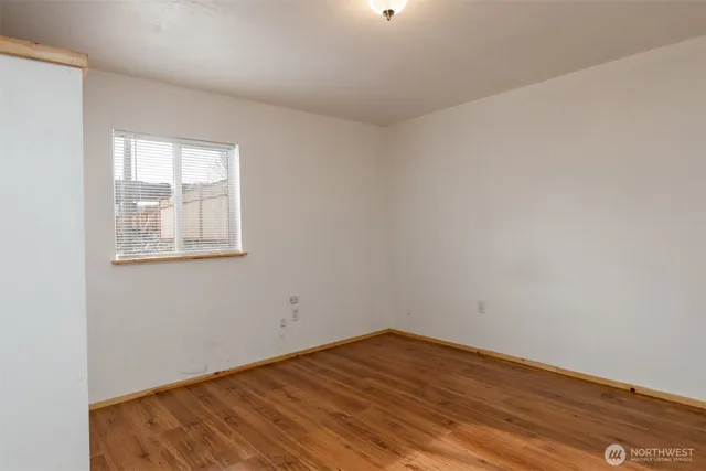 a view of an empty room with wooden floor and closet