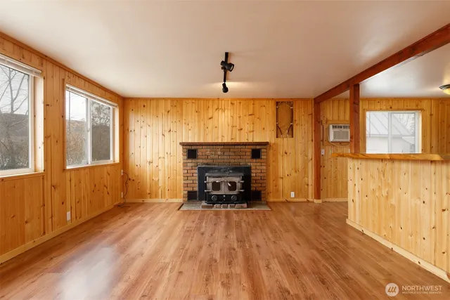 an empty room with windows fireplace and wooden floor