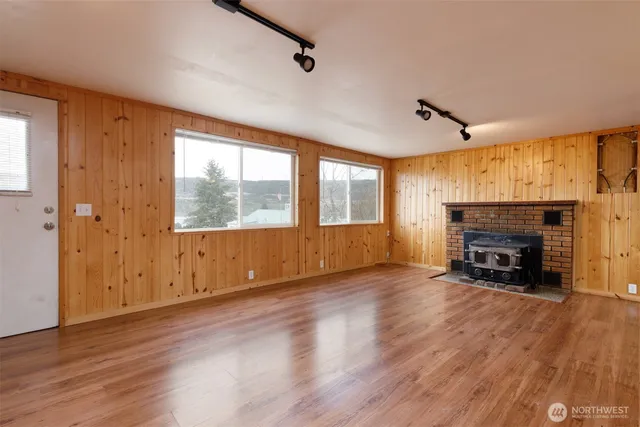 a view of an empty room with a window and wooden floor