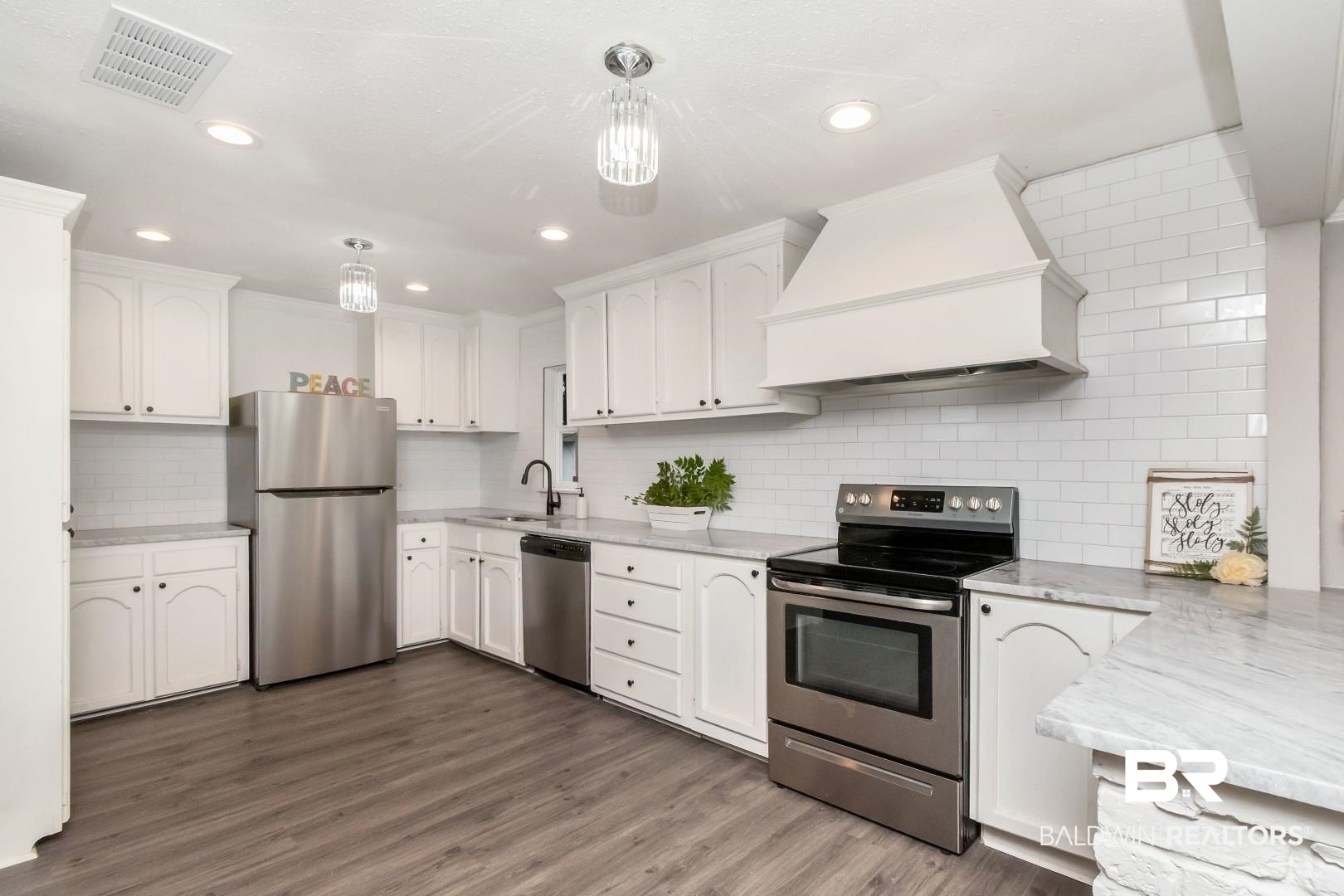 1334 Leroy Stevens Road Mobile, AL 36695 - Photo 13 of 46 Kitchen with appliances with stainless steel finishes, custom range hood, white cabinets, dark wood-style flooring, and decorative backsplash