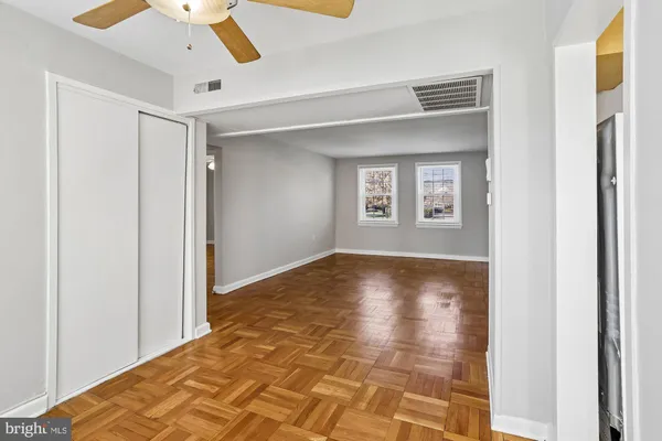 a view of empty room with wooden floor and fan
