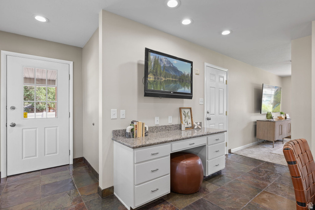 2370 Quail Run Circle East Sandy, UT 84093 - Photo 10 of 54 Built-in desk area featuring a granite countertop, white cabinetry with silver hardware, and slate tile flooring