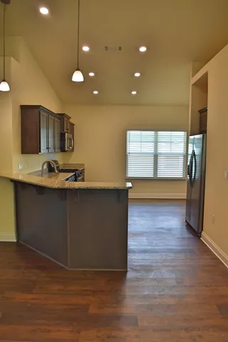 a kitchen with stainless steel appliances granite countertop a sink a stove and a wooden floors