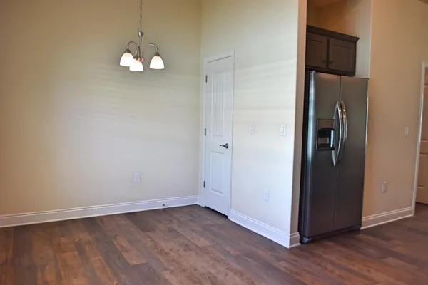 an empty room with wooden floor a mirror and a chandelier