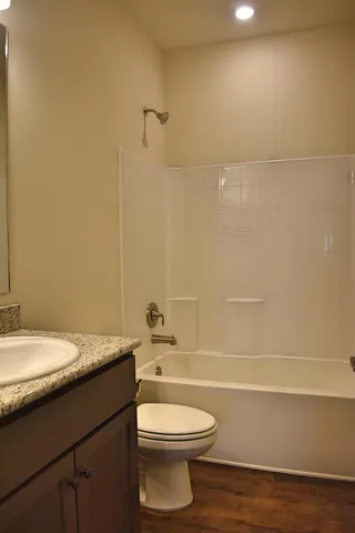 a bathroom with a granite countertop toilet a sink and a bathtub
