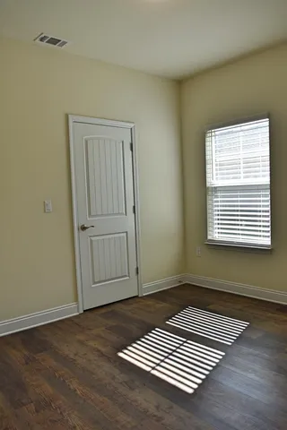 an empty room with wooden floor a rug and a window