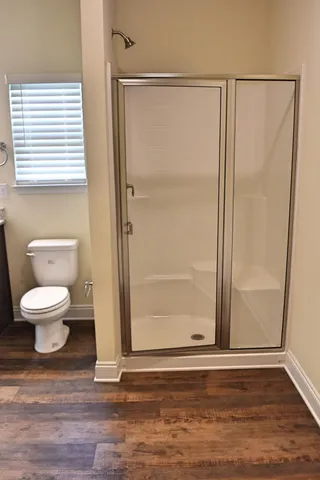 a bathroom with a toilet a window and shower