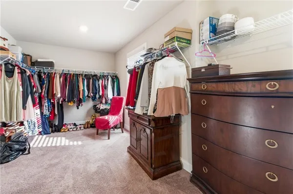 a view of walk in closet with clothes and shoes
