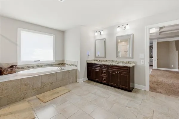 a spacious bathroom with a tub sink and mirror