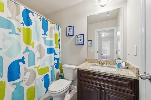 a bathroom with a granite countertop toilet and a sink