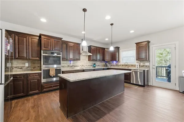 a kitchen with stainless steel appliances granite countertop a stove a sink dishwasher a refrigerator and a oven with wooden floor