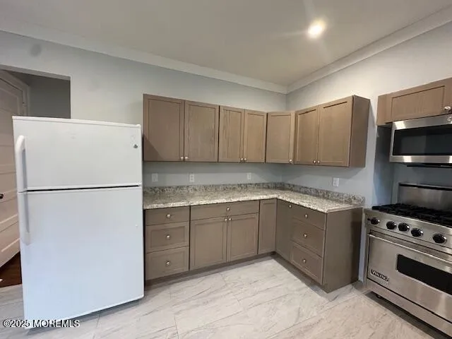 a kitchen with granite countertop a refrigerator and a stove top oven