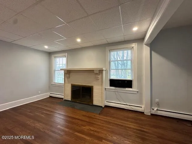 an empty room with wooden floor a fireplace and windows