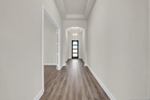 a view of a hallway with wooden floor and a bathroom
