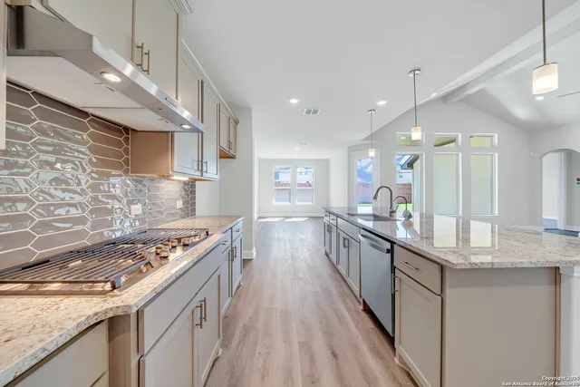 a kitchen with stainless steel appliances granite countertop a stove a sink dishwasher and a refrigerator