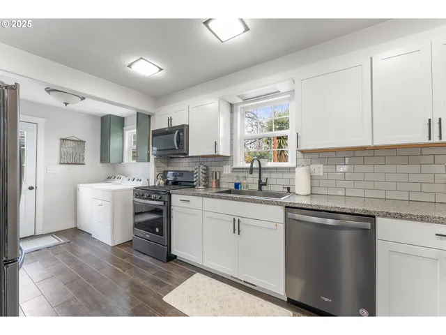 a kitchen with a sink cabinets stainless steel appliances and a window