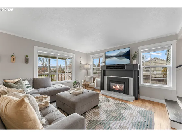 a living room with furniture a fireplace and a flat tv screen next to a window