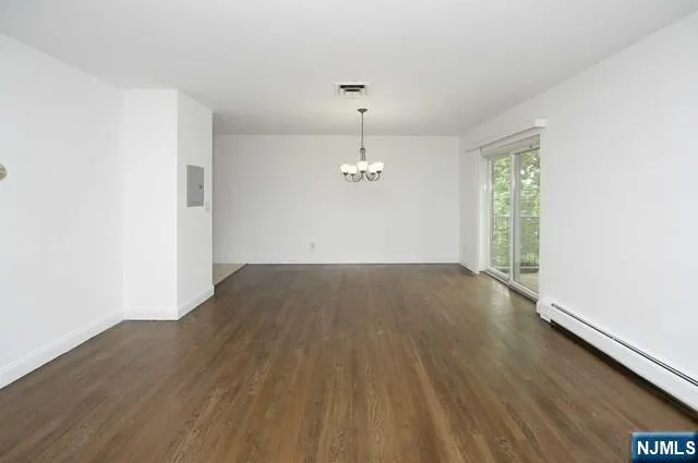 an empty room with wooden floor ceiling fan and windows