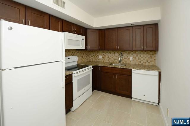 20-30 Ridge Road, Unit A11 Ridgewood, NJ 07450 - Photo 7 of 16 a kitchen with stainless steel appliances granite countertop white refrigerator stove a sink and dishwasher