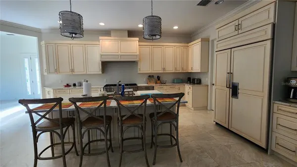 a kitchen with stainless steel appliances granite countertop a dining table chairs refrigerator and sink