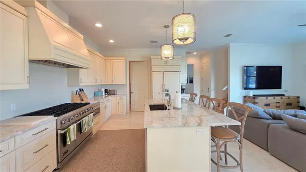 a kitchen with stainless steel appliances granite countertop a stove and a view of living room