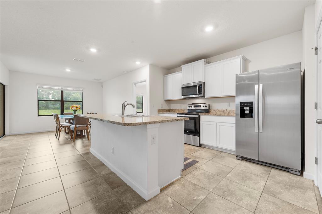 6295 Northwest Regent Street Port St. Lucie, FL 34983 - Photo 4 of 22 a kitchen with white cabinets and refrigerator