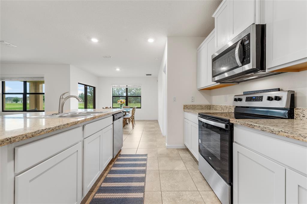 6295 Northwest Regent Street Port St. Lucie, FL 34983 - Photo 5 of 22 a kitchen with stainless steel appliances granite countertop a sink and a stove top oven with granite countertops