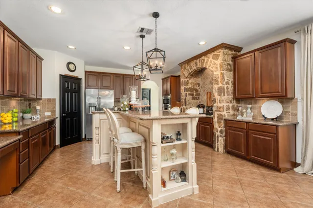 a kitchen with stainless steel appliances granite countertop a stove top oven cabinets a refrigerator and a sink