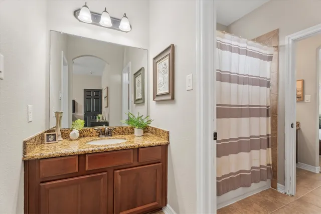 a bathroom with a granite countertop sink two mirror and shower