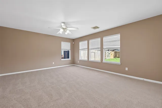 an empty room with windows and ceiling fan