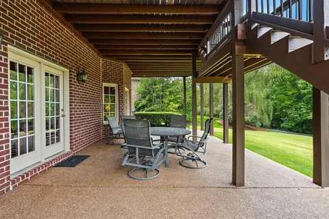 a view of a patio with table and chairs and floor to ceiling window with plants