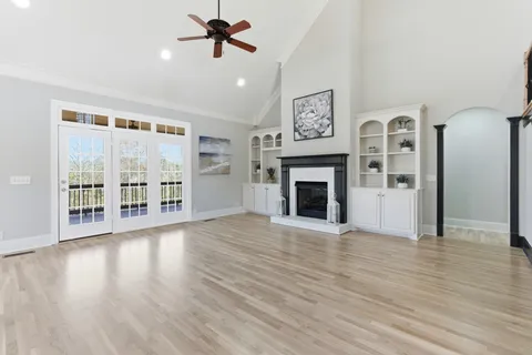 a view of an empty room with wooden floor and a fireplace