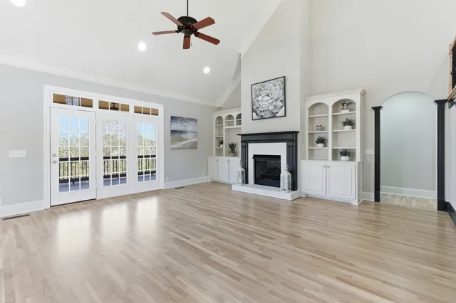 a view of an empty room with wooden floor and a fireplace