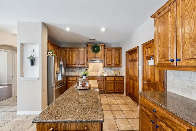 a kitchen with stainless steel appliances granite countertop a refrigerator a stove and a sink