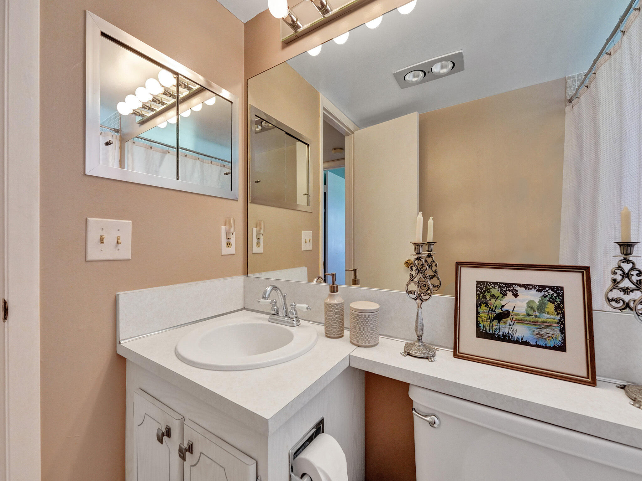 232 Farnham J, Unit 232 Deerfield Beach, FL 33442 - Photo 28 of 38 a bathroom with a sink and a mirror with a painting on the wall