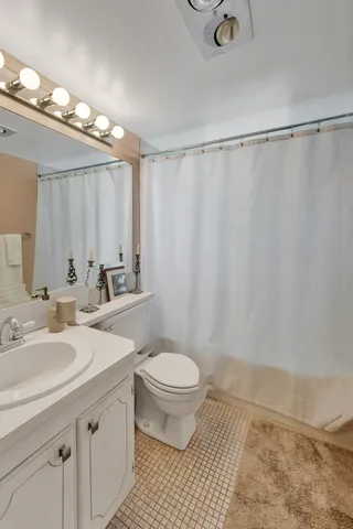 a bathroom with a sink a toilet a mirror and shower