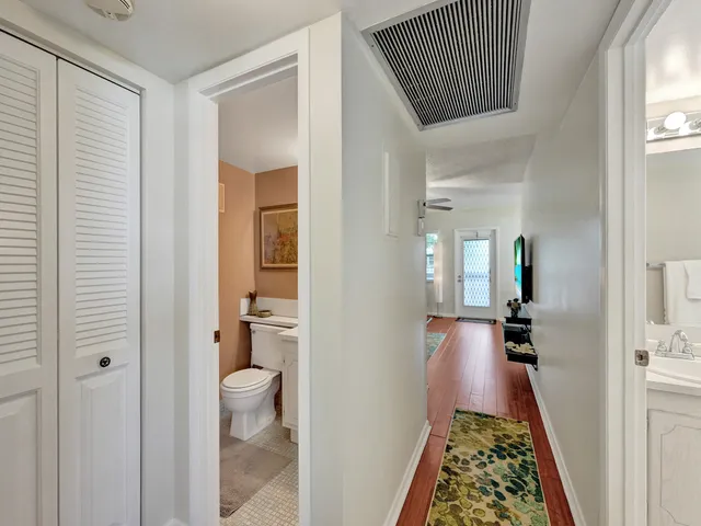 a view of a hallway with bathroom and wooden floor