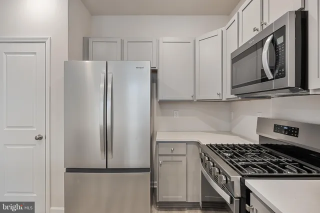 a kitchen with stainless steel appliances granite countertop a refrigerator and a stove top oven