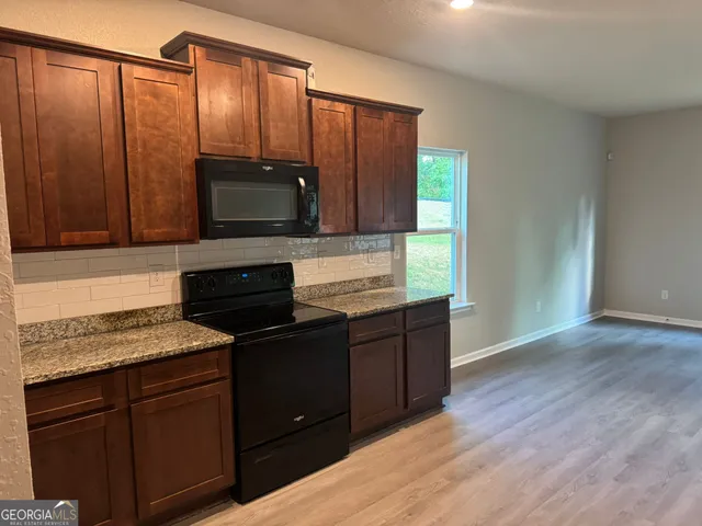 a kitchen with granite countertop wooden cabinets and a stove top oven