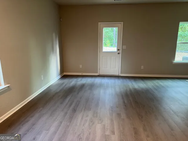 a view of an empty room and wooden floor and a window