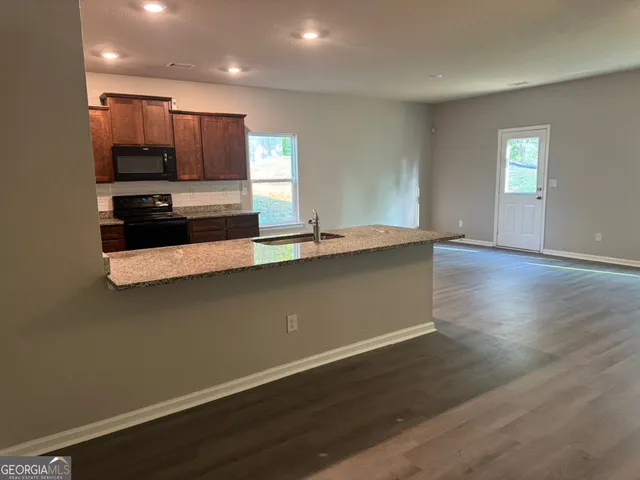 an open kitchen with kitchen island a sink and wooden floor