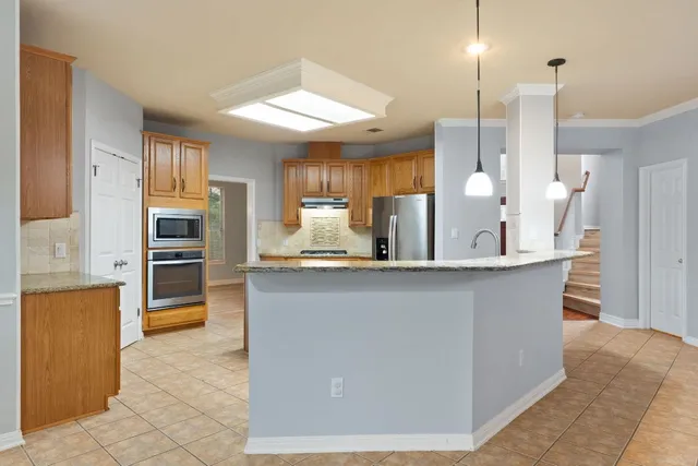 a kitchen with stainless steel appliances granite countertop a refrigerator a sink a stove and oven