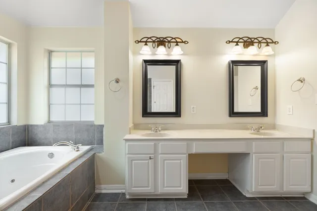 a bathroom with a double vanity sink mirror and bathtub