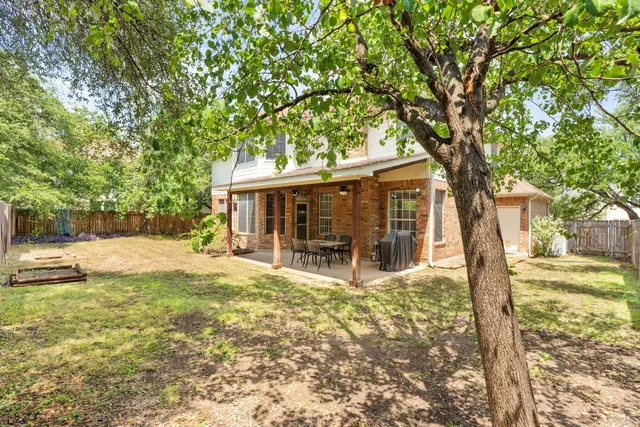 a view of a house with backyard and a tree