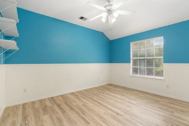 an empty room with windows and fan