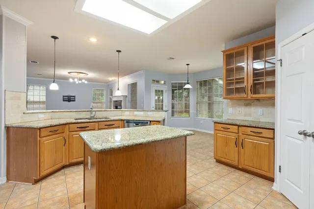 a large kitchen with granite countertop a sink and white cabinets
